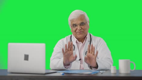 Happy-Indian-senior-doctor-talking-to-the-patient-Green-screen