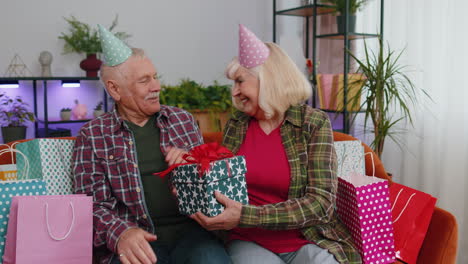 Happy-senior-grandmother-wife-giving-birthday-gift-box-surprise-present-to-her-husband-grandfather