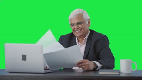 Happy-Indian-senior-manager-reading-business-reports-Green-screen