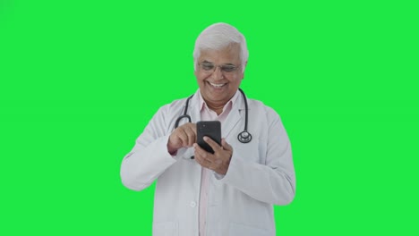 Feliz-Médico-Senior-Indio-Desplazándose-Por-La-Pantalla-Verde-Del-Teléfono