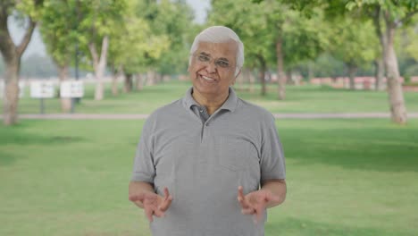 Happy-Indian-old-man-talking-to-someone-in-park