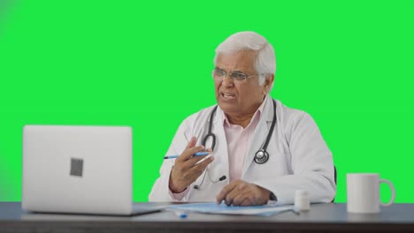 Angry-Indian-senior-doctor-consulting-patient-on-video-call-Green-screen