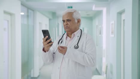 Serious-Indian-senior-doctor-consulting-patient-over-video-call