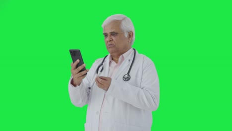 Serious-Indian-senior-doctor-consulting-patient-over-video-call-Green-screen