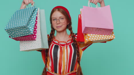 Ginger-girl-showing-shopping-bags,-advertising-discounts,-smiling-looking-amazed-with-low-prices