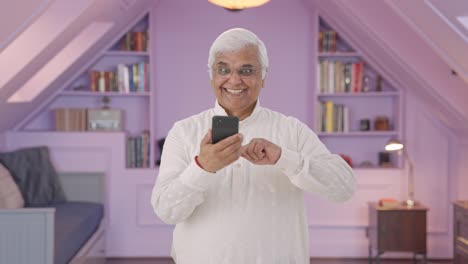 Cheerful-Indian-old-man-scrolling-through-phone