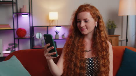 Mujer-De-Pelo-Rojo-Disfrutando-De-Una-Llamada-De-Teléfono-Inteligente-Hablando,-Conversación-De-Teléfono-Móvil-Con-Amigos-En-Casa