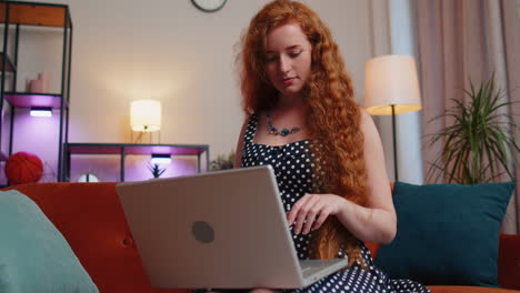 Rothaarige-Junge-Frau-Sitzt-Auf-Dem-Sofa-Und-Schließt-Den-Laptop-PC,-Nachdem-Sie-Die-Arbeit-Im-Wohnzimmer-Zu-Hause-Beendet-Hat