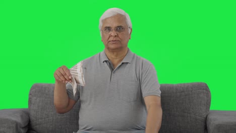 Confident-Indian-old-man-using-money-as-fan-Green-screen