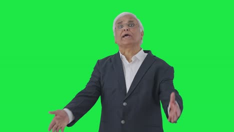 Angry-Indian-senior-journalist-pointing-at-green-screen-and-reading-news