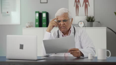 Médico-Senior-Indio-Tenso-Leyendo-Informes-De-Salud