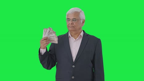 Confident-Indian-senior-manager-using-money-as-fan-Green-screen