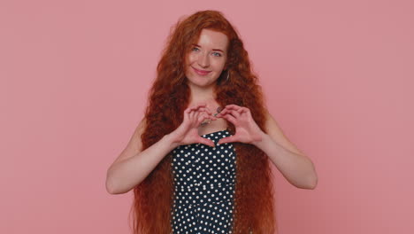 Smiling-ginger-girl-makes-heart-gesture-demonstrates-love-sign-expresses-good-feelings-and-sympathy