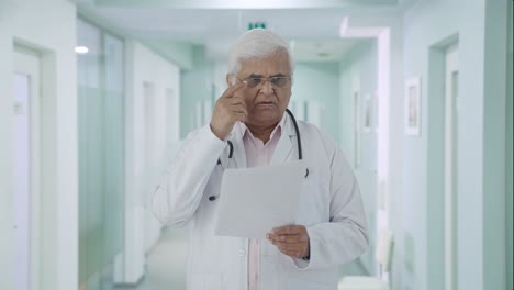 Confundido-Médico-Senior-Indio-Leyendo-Informes