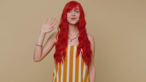 Redheaded-woman-smiling-friendly-at-camera-and-waving-hands-gesturing-hello-or-goodbye,-welcoming