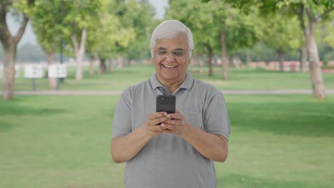 Happy-Indian-old-man-chatting-with-someone-in-park