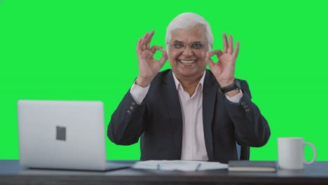 Happy-senior-Indian-businessman-showing-okay-sign-Green-screen