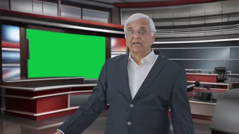 Indian-senior-journalist-pointing-at-green-screen-and-reading-news