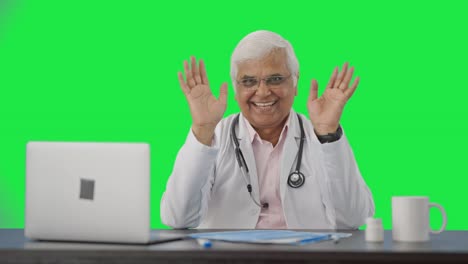 Happy-Indian-senior-doctor-waving-and-saying-Hello-Green-screen