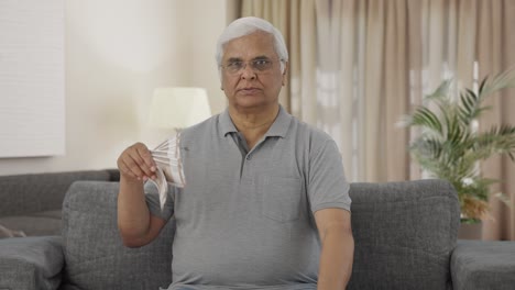 Confident-Indian-old-man-using-money-as-fan