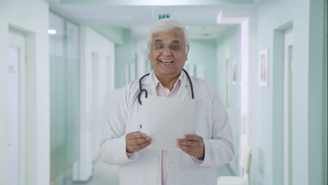 Happy-Indian-senior-doctor-reading-reports