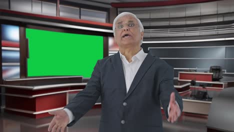 Angry-Indian-senior-journalist-pointing-at-green-screen-and-reading-news