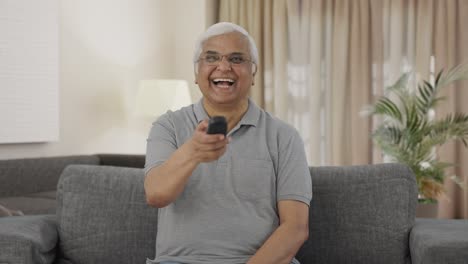 Happy-Indian-old-man-watching-TV-and-laughing