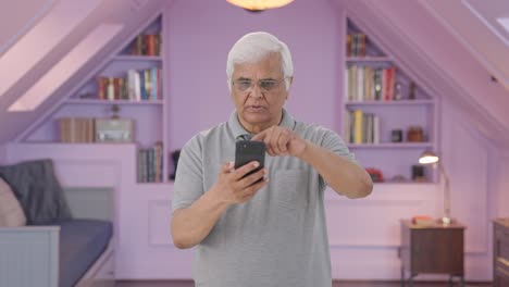 Indian-old-man-scrolling-through-phone