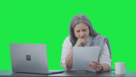 Serious-Indian-senior-female-manager-reading-business-reports-Green-screen