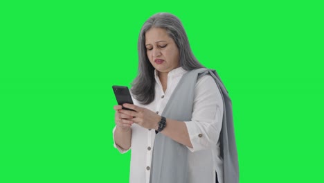 Angry-Indian-senior-businesswoman-chatting-on-phone-Green-screen