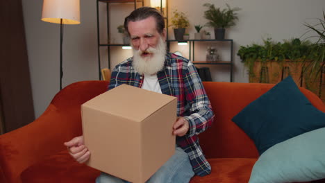 Happy-senior-man-shopper-unpacking-cardboard-box-delivery-parcel-online-shopping-purchase-at-home