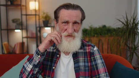 Close-up-of-happy-beautiful-bearded-senior-elderly-grandfather-man-smiling-looking-at-camera-at-home