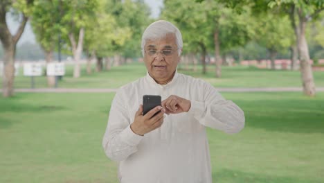 Un-Anciano-Indio-Somnoliento-Desplazándose-Por-El-Teléfono-En-El-Parque