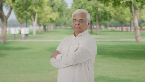 Portrait-of-Confident-Indian-old-man-standing-crossed-hands-in-park