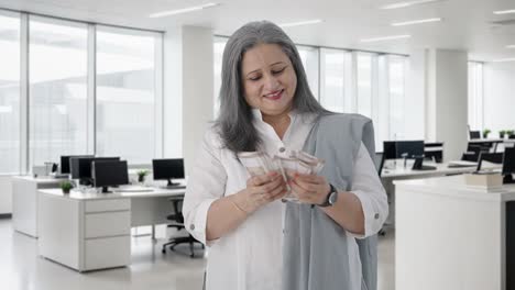 Happy-Indian-senior-businesswoman-counting-money