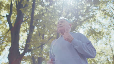 Senior-athletic-man-grandfather-running-jogging-in-sunny-park-during-morning-workout-cardio-outdoors