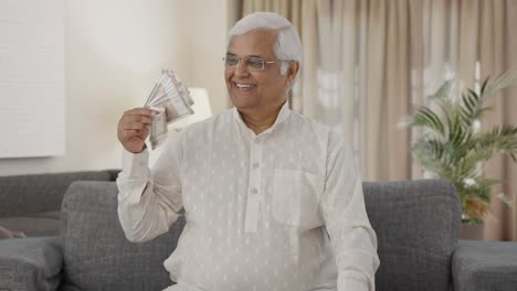 Happy-Indian-old-man-using-money-as-fan