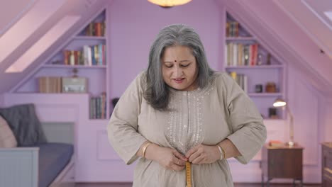 Happy-Indian-old-woman-measuring-waist-using-inch-tape