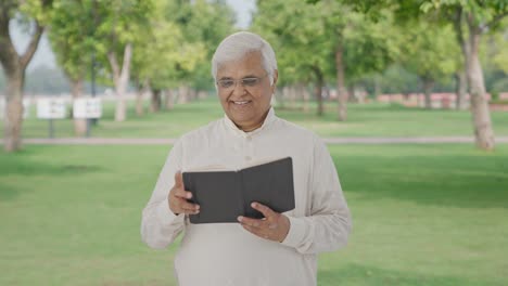 Happy-Indian-old-man-reading-a-book-in-park