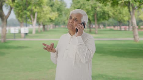 Indian-old-man-talking-on-phone-in-park