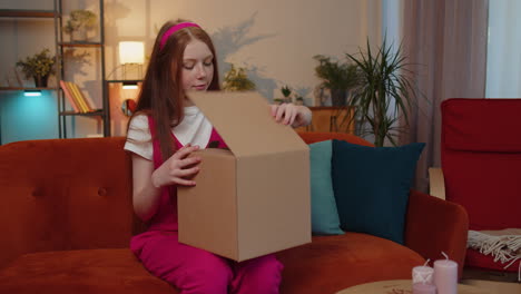 Happy-child-girl-shopper-unpacking-cardboard-box-delivery-parcel-online-shopping-purchase-at-home