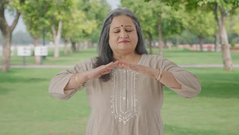 Happy-Indian-old-woman-doing-breathe-in-breathe-out-exercise-in-park