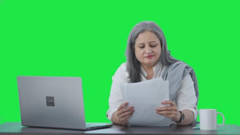 Happy-Indian-senior-female-manager-reading-business-reports-Green-screen