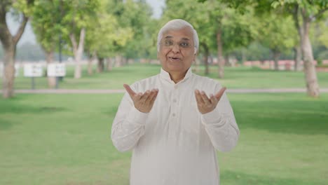 Happy-Indian-old-man-talking-to-someone-in-park