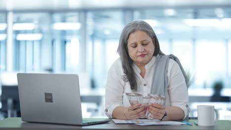 Indian-senior-businesswoman-counting-money