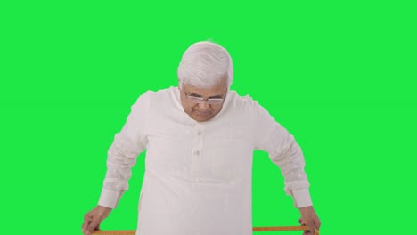 Sad-Indian-old-man-measuring-waist-using-inch-tape-Green-screen