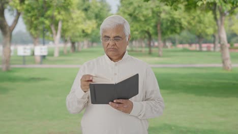 Confused-Indian-old-man-reading-a-book-in-park