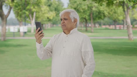 Indian-old-man-talking-on-video-call-in-park