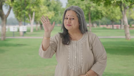 Happy-and-cheerful-Indian-old-woman-waving-and-saying-hello-in-park