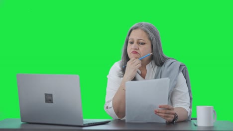 Confused-Indian-senior-female-manager-reading-business-reports-Green-screen